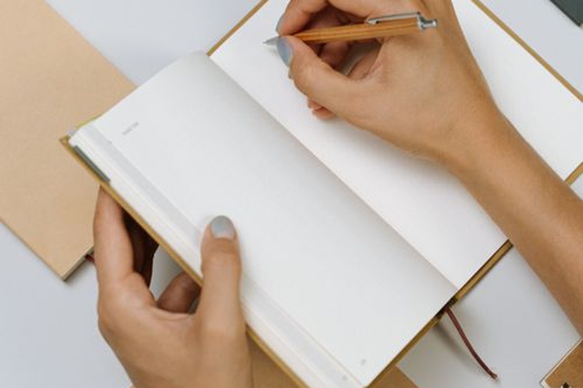 Person writing daily habits in a notebook for habits to track