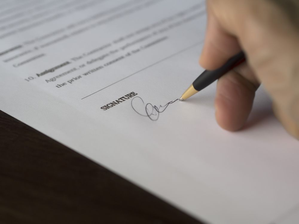 A hand signing a formal document